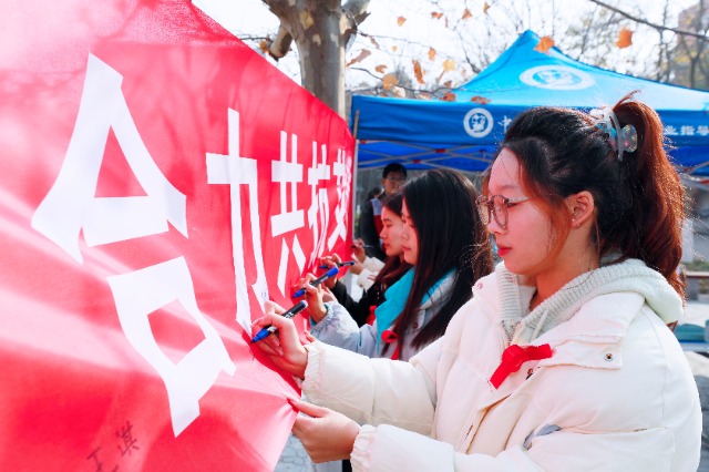 20231127中國(guó)石油大學(xué)（華東）青年學(xué)子在合力共抗艾滋的條幅上簽字，表達(dá)抗擊艾滋病的決心和信心  .jpg