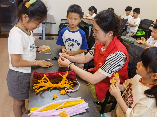 7月12日，在泰州市海陵區(qū)城東街道林湖社區(qū)，泰州市大浦小學(xué)“綠葉”暑期公益班的老師正在教孩子們一起做手工2（拍攝者：泰州市大浦中心小學(xué)  陳惠婷）.jpg